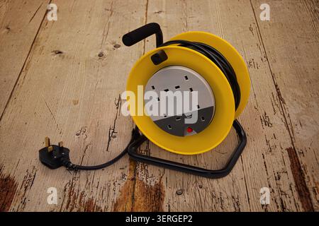 A mains electricity extension cable reel with multiple three pin sockets placed on an old boarded wooden floor Stock Photo