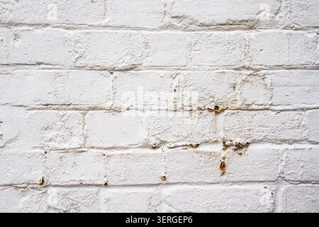 A dirty old white painted brick wall background with rust marks from items previously fixed to it Stock Photo