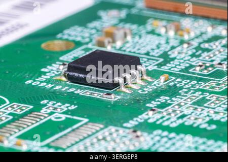 Close-up macro view of a black integrated circuit on a green printed circuit board. Stock Photo