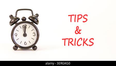 Tips and tricks words symbol. Concept words Tips and tricks on beautiful white paper. Beautiful white background. Black alarm clock. Business tips and Stock Photo