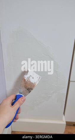 Putty Knife with Plaster Paste on Damaged Wall Stock Photo