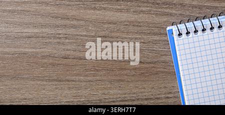 Top view of a spiral notebook with graph paper placed on a wooden desk, leaving ample copy space for notes, planning, education, or office concepts. Stock Photo