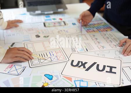 Creative designers sketching mobile app wireframe templates on paper in office Stock Photo