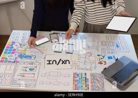 UX UI designers collaborating on mobile app wireframe templates in office Stock Photo