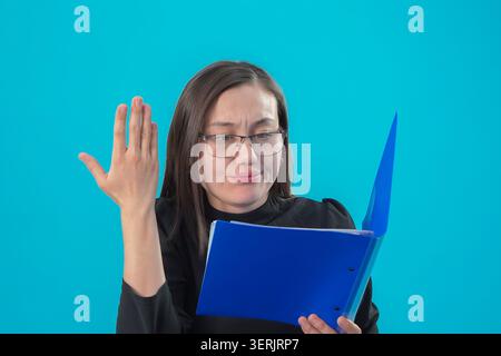 Woman holding blue folder and gesturing with hand in studio Stock Photo