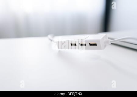 Close-up of modern white USB hub splitter on minimalist desk. Bright, high key lighting with shallow depth of field. Clean technology concept for Stock Photo