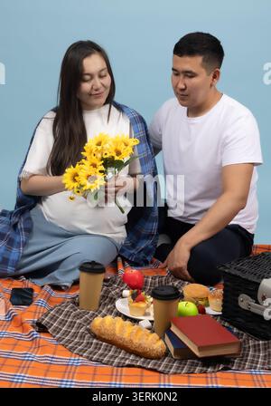 Young couple having a picnic with flowers in a park Stock Photo