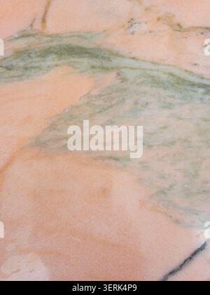 The surface presents a blend of pastel pink marble with green and olive mineral inclusions. This stone can be used for interior design projects and de Stock Photo