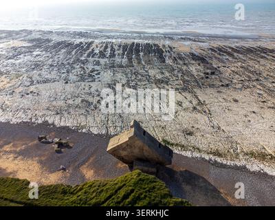 A spectacular aerial view from the cliff edge shows the tilted German bunker on the beach, while the low tide reveals a vast and striking white chalk Stock Photo