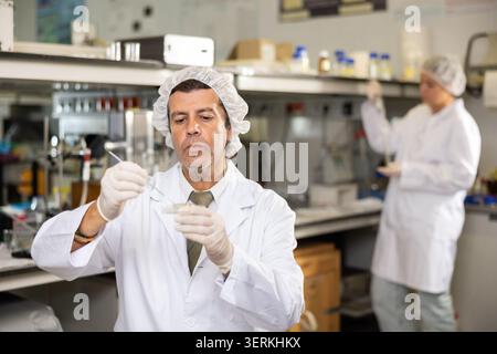 Male chemist working in laboratory, analyzing liquid samples in flasks Stock Photo