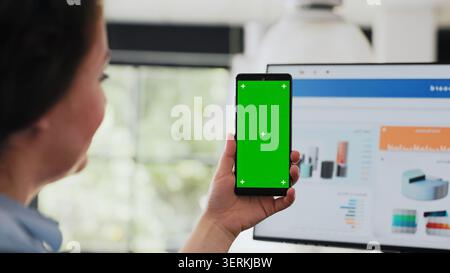 Worker checking green screen display on smartphone, holding device with copy space blank software in coworking space Stock Photo