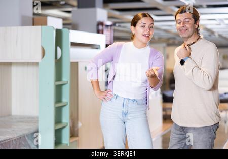 Happy man and woman choosing kids furniture in furniture showroom Stock Photo