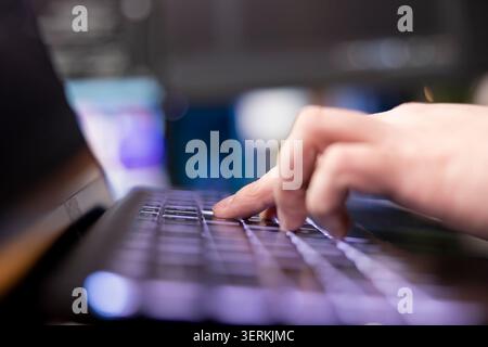 Programmer typing on keyboard, designing and developing software programs, extreme close-up shot. Remote IT employee implementing and maintaining company systems on computer. Stock Photo