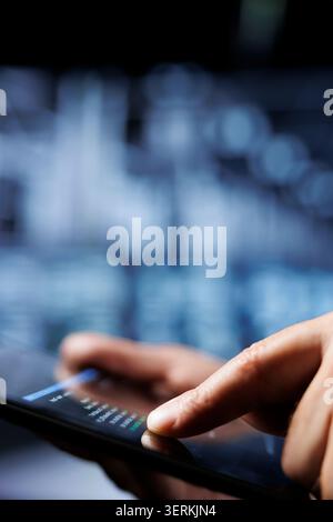 Certified system administrator updates server rigs, writing intricate binary code scripts on tablet. Computer scientist using programming to fortify cybersecurity in high-tech place. Stock Photo