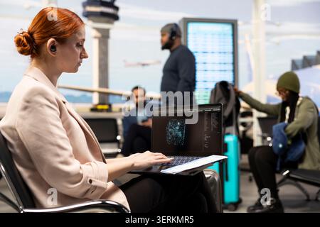 Businesswoman using generative AI, and deep learning models, on computer in airport, exploring big data analytics and automation tools. International business travel with technology focus. Stock Photo