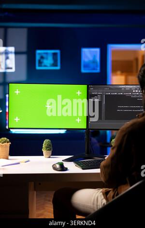 Programmer using green screen computer to secure company servers from virus attacks. IT remote employee writing code, building firewalls protecting data using mockup PC monitor. Stock Photo