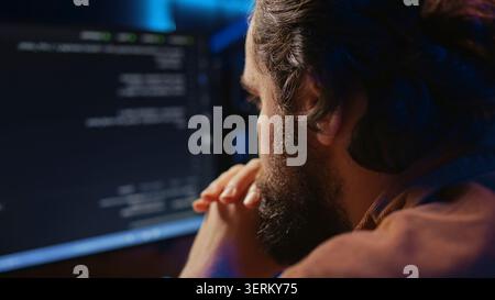 Programmer in home office concentrating on finding bugs while doing coding on computer, extreme close-up shot, iT admin frowning while looking at screen, confused by errors in lines of code. Stock Photo