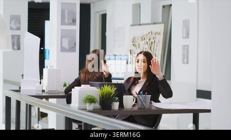 Graphic design consultant who uses holographs to shape layouts, real estate agency, asian designer establishing reconstruction plan using hologram visuals and artificial intelligence. Stock Photo