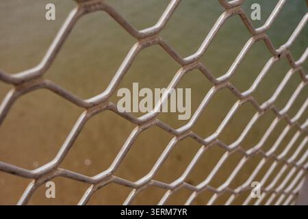 Metal mesh forms repeating hexagonal pattern. Worn surface suggests outdoor use or aging exposure Stock Photo