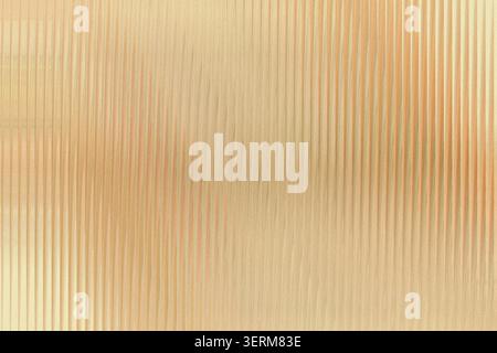 A luxurious golden background with a vertical ribbed or corrugated texture, reflecting light to create depth and a sophisticated metallic appearance. Stock Photo