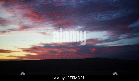 A Vibrant Skyway of Crimson and Violet Twilight Clouds Over Silhouetted Vantage Ridges Stock Photo