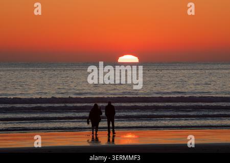 A couple watching the setting sun over the Pacific Ocean, Crescent City, California Stock Photo
