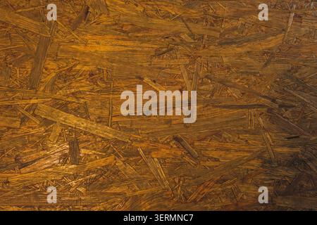 A top-down full-frame shot showing the rough texture and compressed wood strand pattern of an oriented strand board or OSB panel. Stock Photo