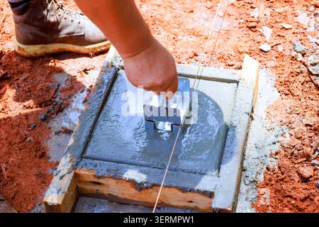 Worker uses tool to level freshly poured concrete at construction site Stock Photo