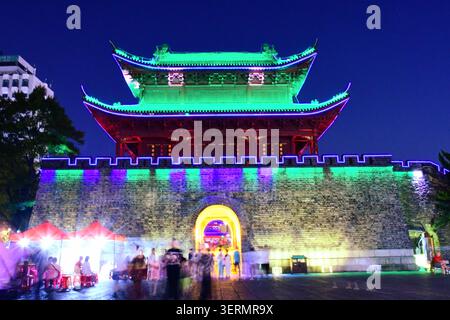 Vibrant night view of the ancient city gate tower in Yueyang, Hunan illuminated with colourful LED lights against a deep indigo evening sky. Stock Photo