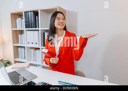 Professional businesswoman reviewing reports, using a tablet and laptop, organizing documents, analyzing business data and managing daily office tasks Stock Photo