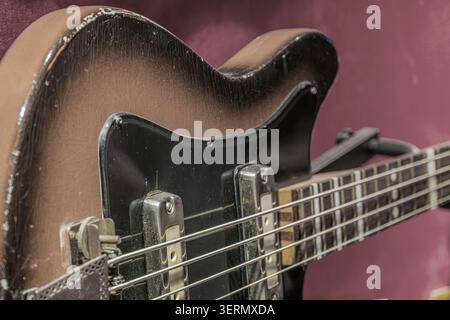 Rich dark brown vintage bass guitar, featuring glossy finish and classic bridge design, highlighting high-quality wood grain detail, metallic strings Stock Photo