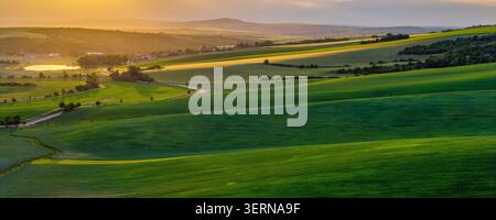 Panoramic aerial view of rolling green hills in South Moravia at golden sunset with a lake Stock Photo