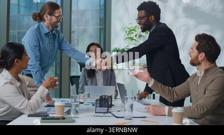 Multinational business team at office meeting. Two diversity businessmen shaking hands men congratulation handshake at corporate briefing success deal Stock Photo