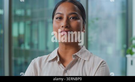 Portrait serious confident Indian business woman looking at camera crossing hands posing indoors in office. Calm Arabian ethnic businesswoman female Stock Photo