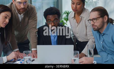 Multiracial business team five diversity managers talk discuss laptop problem at office meeting multiethnic women and men talking looking in computer Stock Photo