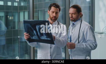 Two specialists Caucasian doctors discussing x-ray cancer health problem medication talking in clinic. Coworkers males men medical practitioners Stock Photo