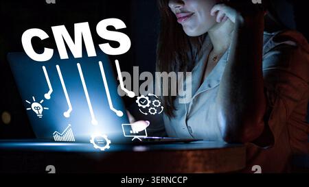 Woman working on a laptop with content management system tools at night in a dark room Stock Photo