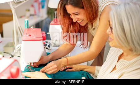 Young woman teaching older student sewing machine skills Stock Photo