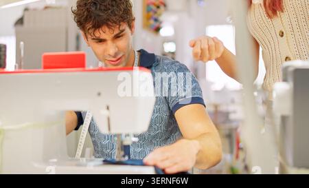 Young man learning sewing in atelier with instructor Stock Photo