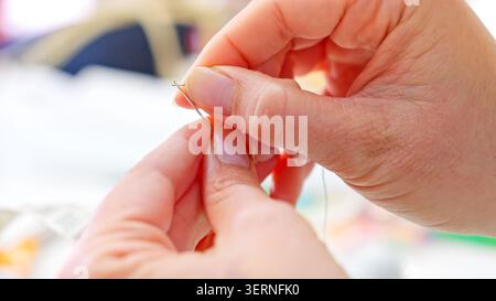 Hands threading needle preparing for sewing crafting workshop Stock Photo