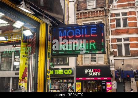 LONDON - MAY 11, 2026: Mobile Repair Shop Brixton – LED “Mobile Repair” sign outside a small high street tech repair shop. Stock Photo