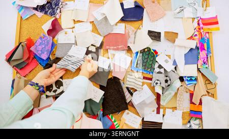 Designer hands choosing fabric swatches on a cork board Stock Photo