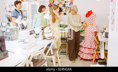 Tailor measuring flamenco dress in sewing workshop with students Stock Photo