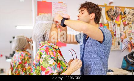 Tailor measuring senior woman's head in workshop Stock Photo