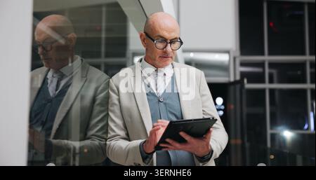 Businessman, scroll and research on tablet at night, investment banking and project deadline on web. Mature person, working late and business analyst Stock Photo