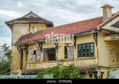 Old abandoned colonial building with peeling yellow paint and a damaged roof Stock Photo