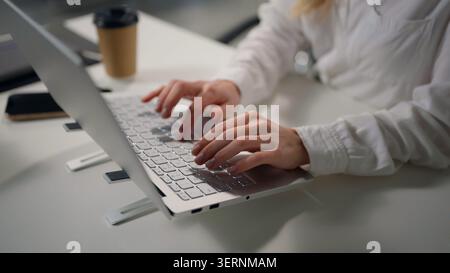 Closeup female hands typing laptop computer unrecognizable business woman working internet chatting e-mail virtual chat using networks at table Stock Photo