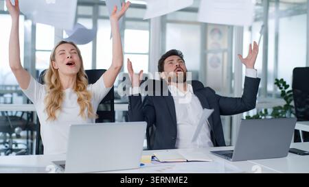 Two business partners throwing papers in air happy partnership at office table Caucasian middle-aged businessman with businesswoman throw documents Stock Photo