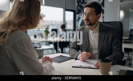 Caucasian leader of company businessman leading business interview writing notes talking with businesswoman candidate woman boss male review resume Stock Photo