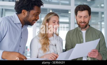Three multiracial business people team marketing group discussing papers happy talk communicating working with documents in office African and Stock Photo